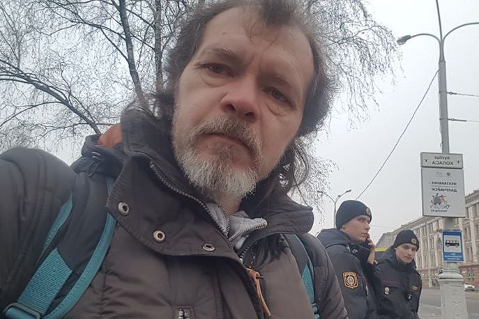 Затрыманы журналіст Аляксандр Зянкоў чакае міліцэйскую машыну.