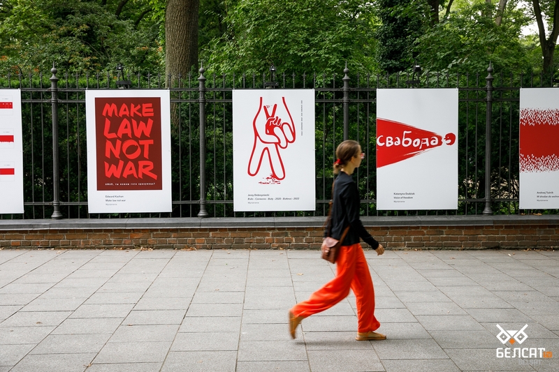 Женщина идет возле ограждения Королевского музея Лазенки, где открылась выставка плаката «Бел-чырвона-белы», посвященная второй годовщине протестов в Беларуси. Варшава, Польша. 9 августа 2022 года. Фото: Татьяна Веремеева / Белсат